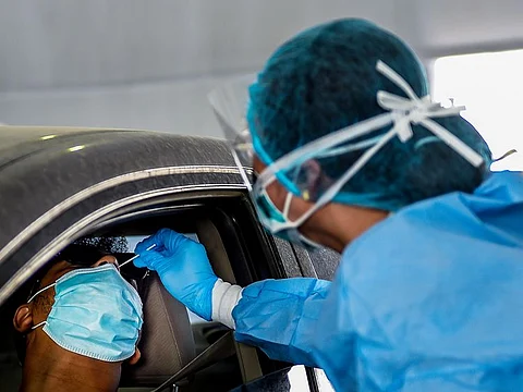 A paramedic staff collects swab samples at a coronavirus drive-through screening center located at Sharjah Golf and Shooters Club. 