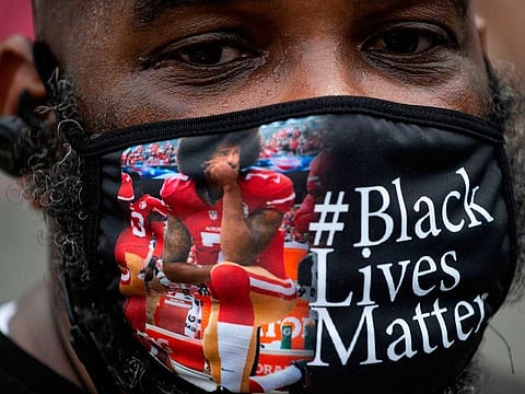 A protester, wearing a face mask featuring Colin Kaepernick kneeling, joins a protest in Washington, DC, against racism and police brutality, on June 6, 2020. 