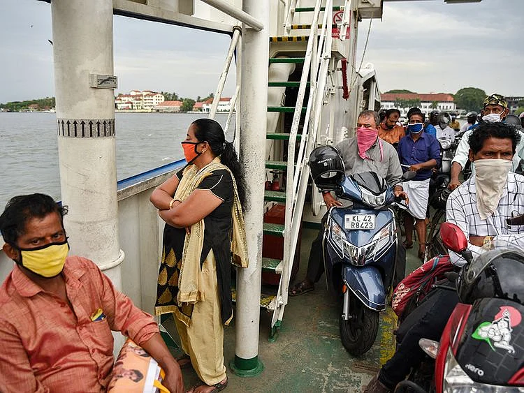 People wearing masks travel in a ferry in Kochi, Kerala
