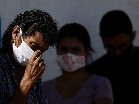 People wear masks as they wait for a quick COVID-19 test, at a testing site set up on a public school's basketball court in the Estrutural neighbourhood of Brasilia, Brazil. AP