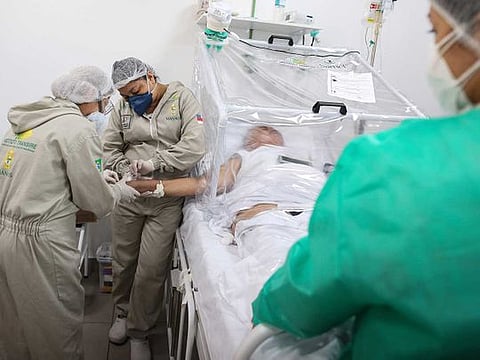 Health workers assist a COVID-19 patient at the Gilberto Novaes Municipal Hospital in Manaus, Brazil.