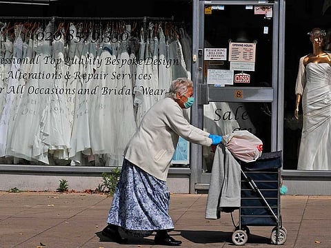 A woman walks past a Wedding dress shop in London, Tuesday, June 9, 2020, where bride dresses pile unused in the shop window. Weddings in the UK have been postponed due to the Covid-19 pandemic and are probably allowed starting in July. 