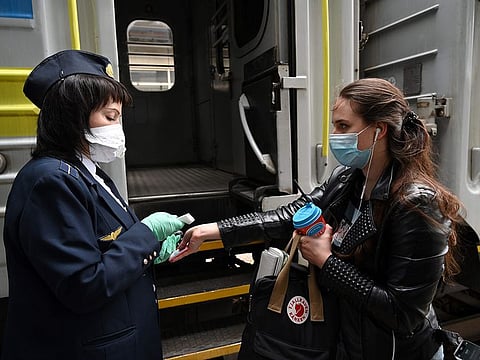 A passenger (R) gets a temperature check before boarding a train at the central railway station in Kiev, on June 1, 2020. 