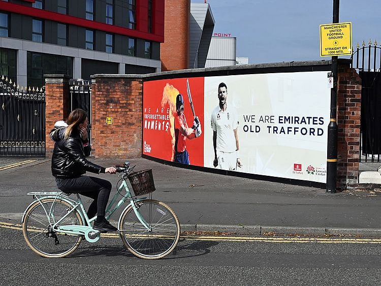 A woman cycles past Old Trafford cricket ground in Manchester where West Indies will play England in a Test series