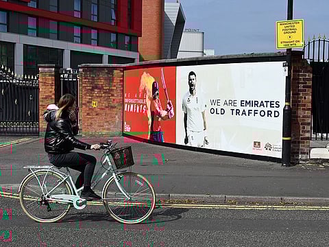 A woman cycles past Old Trafford cricket ground in Manchester where West Indies will play England in a Test series