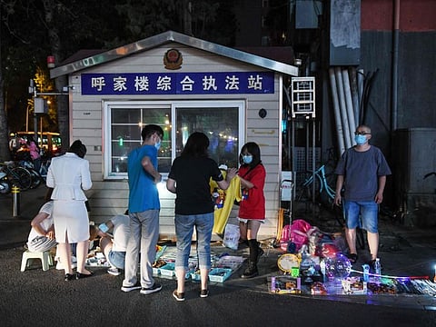 Street vendors sell products to customers beside a police cabin on the roadside in Beijing. The global economy will suffer the biggest peacetime downturn in a century before it emerges next year from a coronavirus-inflicted recession, the OECD said on Wednesday.