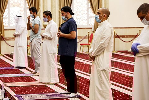 Worshippers, distanced safely from each other and clad in face masks, perform the noon prayers at a mosque in Kuwait City in a file picture.