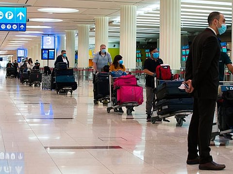 Passengers wearing masks due to the coronavirus pandemic wait at ticketing for flights at Dubai International Airport's Terminal 3.