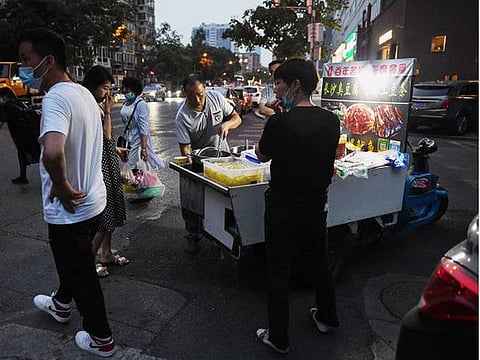 People buy food from a street vendor at an intersection in Beijing on June 9, 2020.