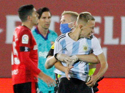 A supporter invades the pitch with Lionel Messi behind during the La Liga match between Mallorca and Barcelona.