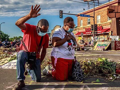 A couple kneels and raises their hands at a memorial for George Floyd following a day of demonstrations on June 13, 2020 in Minneapolis, Minnesota, US.