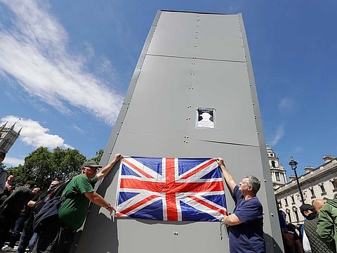 Members of far-right Football Lads Alliance hold a British flag in front of a protective covering surrounding the statue of former British Prime Minister Sir Winston Churchill in Parliament Square, central London, Saturday, June 13, 2020. British police have imposed strict restrictions on groups planning to protest in London Saturday in a bid to avoid violent clashes between protesters from the Black Lives Matter movement, as well as far-right groups.