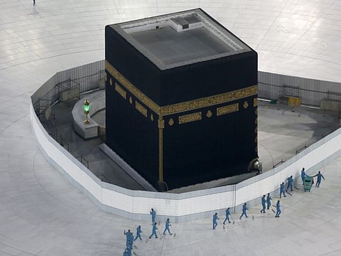 In this March 7, 2020 file photo, workers disinfect the ground around the Kaaba in Mecca, Saudi Arabia after authorities emptied Islam's holiest site for sterilisation over fears of the new coronavirus. 
