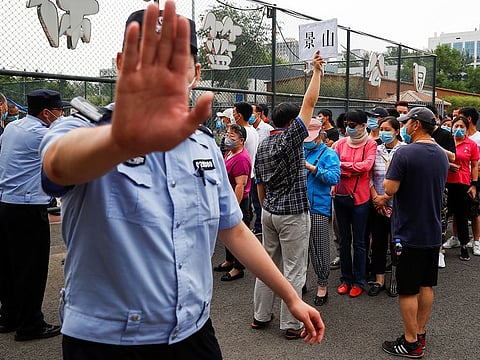 A police officer gestures at a photographer as people line up to get a nucleic acid test at a sport center after a spike of cases of the coronavirus disease (COVID-19), in Beijing, China June 17, 2020. 