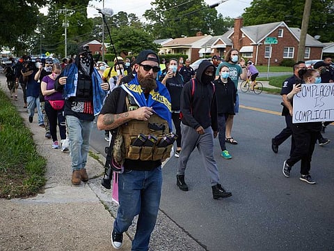 In this file photo a member of the far-right militia, Boogaloo Bois, walks next to protestors demonstrating outside Charlotte Mecklenburg Police Department Metro Division 2 just outside of downtown Charlotte, North Carolina, on May 29, 2020. A far-right movement whose followers have appeared heavily armed at recent US protests has suddenly become one of the biggest worries of law enforcement, after one killed two California police officers.