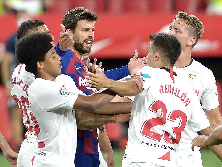 Barcelona's Spanish defender Gerard Pique (C) argues with Sevilla's Spanish defender Sergio Reguilon (R) during the Spanish league football match between Sevilla FC and FC Barcelona at the Ramon Sanchez Pizjuan stadium in Seville on June 19, 2020. (Photo by CRISTINA QUICLER / AFP)