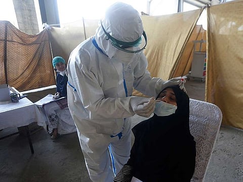 A health worker takes a nasal swab sample at a screening centre for the new coronavirus, in Lahore, Pakistan, Thursday, June 18, 2020. 