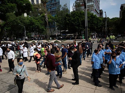Employees stand outside of their work building after a 7.5 earthquake, in Mexico City, Tuesday, June 23, 2020. The earthquake centered near the resort of Huatulco in southern Mexico swayed buildings Tuesday in Mexico City and sent thousands into the streets.