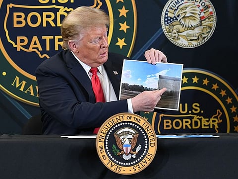 US President Donald Trump shows a photo of the US/Mexico border wall as he speaks during a roundtable briefing on border security at the United States Border Patrol Yuma Station in Yuma, Arizona.