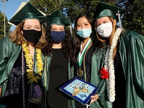 New West Charter School graduates smile beneath their masks to prevent coronavirus after their drive-by graduation in Stoner Park in Los Angeles on June 10, 2020. 