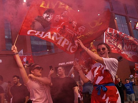 Fans celebrate Liverpool winning the Premier League title following Chelsea’s 2-1 victory over Manchester City, outside Anfield in Liverpool on June 25, 2020. 