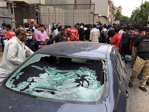  A police officer (L) surveys the site of an attack at the Pakistan Stocks Exchange entrance in Karachi.