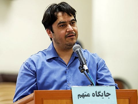 In this June 2, 2020 photo, journalist Ruhollah Zam speaks during his trial at the Revolutionary Court, in Tehran, Iran. The judiciary spokesman, Gholamhossein Esmaili, announced Tuesday, June 30, 2020 that Zam, a journalist whose online work helped inspire the 2017 economic protests and who returned from exile to Tehran was sentenced to death. The Persian writing on the podium reads, "defendant's place." (Ali Shirband/Mizan News Agency via AP)