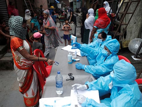 A healthcare worker checks the temperature of a resident during a medical campaign for the coronavirus disease (COVID-19) at a slum area in Mumbai, India, June 30, 2020. 