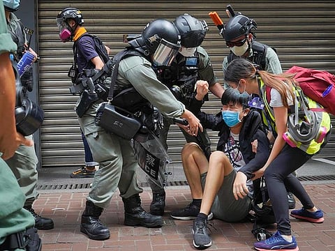 A reporter is helped by police and others after being with sprayed pepper spray in Causeway Bay before the annual handover march in Hong Kong, Wednesday, July. 1, 2020. Hong Kong marked the 23rd anniversary of its handover to China in 1997, and just one day after China enacted a national security law that cracks down on protests in the territory.