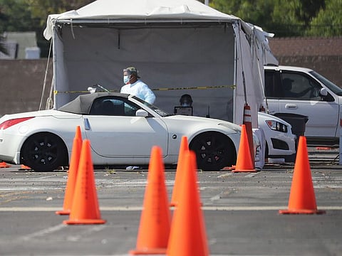 A worker passes a specimen bag to a motorist at a drive-in COVID-19 testing site at Crenshaw Christian Center amid the coronavirus pandemic on July 1, 2020 in Los Angeles, California.