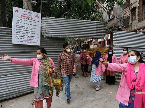 Workers with Accredited Social Health Activist (ASHA) from India's National Rural Health Mission wearing pink robes and protective masks walk through a street as they conduct a door-to-door survey on the coronavirus in New Delhi, India, on July 2, 2020.