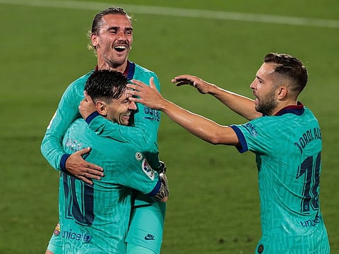 Barcelona's Antoine Griezmann, top, is congratulated by teammate Lionel Messi, left, and Jordi Alba, right, after scoring.