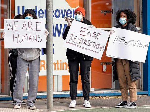 Women hold signs outside housing commission apartments under lockdown in Melbourne, Australia, on Monday, July 6, 2020. The leader of Australia’s most populous state says her government’s decision to close its border with hard-hit Victoria state marks a new phase in the country’s coronavirus pandemic.