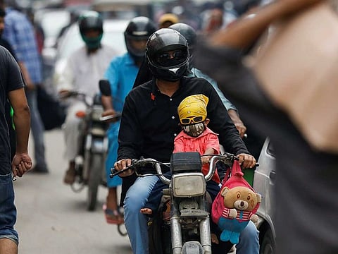 A boy wears a protective face mask as he rides on a motorcycle with a member of his family along a road, as the outbreak of the coronavirus disease (COVID-19) continues, in Karachi, Pakistan.