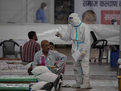 A health official wearing Personal Protective Equipment (PPE) suit talks to patients inside the campus hall of spiritual organisation Radha Soami Satsang Beas (RSSB), converted into a COVID-19 coronavirus care centre in New Delhi on July 6, 2020. 