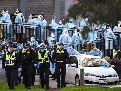 Police officers and healthcare workers are stationed outside a public housing tower that is locked down as a coronavirus hotspot in Melbourne, Australia, Wednesday, July 8, 2020. Australian Prime Minister Scott Morrison says a shutdown of the nation's second-largest city is necessary and promised continuing financial support for businesses that fear they won't survive a second lockdown. 