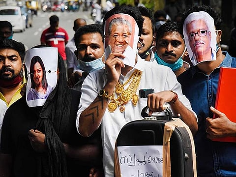 Youth Congress activists hold pictures of Kerala Chief Minister Pinarayi Vijayan (C), former UAE consulate officer Swapna Suresh (L), and State IT Secretary M Sivasankar (R) during a protest over the Kerala gold smuggling case, in Kochi, Tuesday, July 7, 2020. 