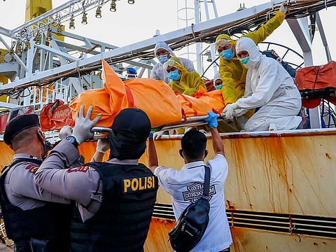 Officials transferring the body of an Indonesian crew member found on board following the search of a Chinese-flagged fishing vessel.