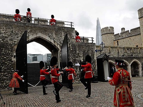 Yeoman Warders open the gates for a drawbridge to then be lowered, as they take part in a ceremony with guardsmen to mark the reopening of the Tower of London for visitors, in London, as the British government continues to relax its coronavirus restrictions, Friday, July 10, 2020.