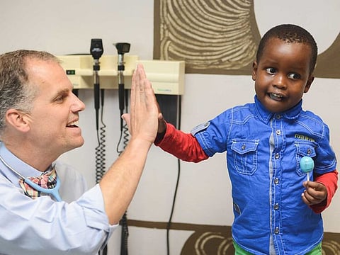 A patient high fives Dr. Alan Anderson after a check-up following treatment for kidney cancer.  Dr. Anderson is one of the pediatric oncologists from Texas ChildrenÕs Hospital who will help train the estimated 4,800 African healthcare professionals as part of the Global HOPE (Hematology-Oncology Pediatric Excellence) initiative.   Photo credit: Barcode Media