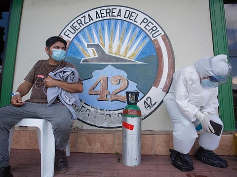 A medical worker (L) showing symptoms of the novel coronavirus COVID-19, waits for an ambulance with a relative wearing a protective suit in Iquitos, in the Amazon Forest in northern Peru, upon arriving on a plane from San Isidro community. Peru surpassed 320,000 cases of the novel coronavirus on July 11, while around 12,000 COVID-19 patients remain hospitalised and more than 11,600 have died. Peru, with 33 million inhabitants, is the second country in Latin America with the most cases of COVID-19, behind Brazil, and stands fifth in the world.