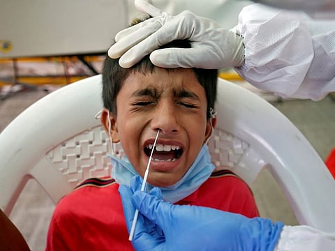 A boy reacts as a healthcare worker takes a swab from him for a rapid antigen test to tackle the coronavirus disease (COVID-19) outbreak, at a check-up point on a national highway in Ahmedabad, India, July 13, 2020.
