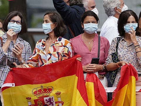 Masked women hold Spanish flags as King Felipe and Queen Letizia visit the Guggenheim Museum in Bilbao, as part of a tour to promote tourism in Spain, on July 17, 2020.