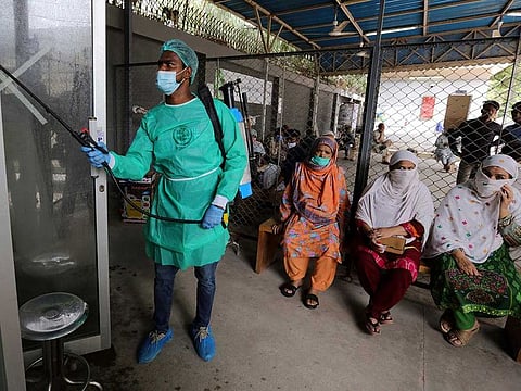 A worker sprays disinfectant on a booth at a testing and screening facility for the new coronavirus, in a hospital in Karachi, Pakistan, Friday, July 17, 2020.