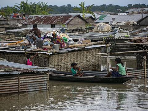 A flood affected family takes shelter on the roof of their partially submerged house along river Brahmaputra in Morigaon district, Assam, India, on July 16, 2020. 