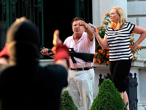 In this June 28, 2020 file photo, armed homeowners Mark and Patricia McCloskey, standing in front their house along Portland Place confront protesters marching to St. Louis Mayor Lyda Krewson's house in the Central West End of St. Louis. 