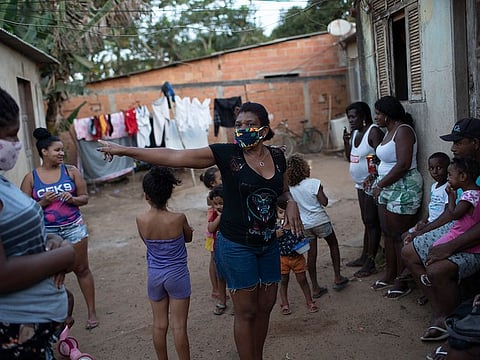 Residents gather as donated food, kits of cleaning products and protective face masks are distributed amid the new coronavirus pandemic at the Maria Joaquina "Quilombo" in Cabo Frio, on the outskirts of Rio de Janeiro, Brazil, Sunday, July 12, 2020.