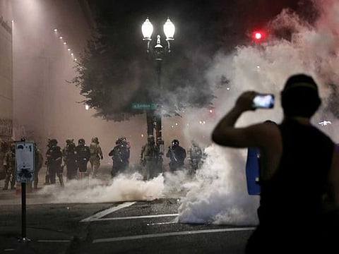 A demonstrator holds a mobile phone in front of  federal law enforcement officials during a protest against racial inequality in Portland, Oregon, U.S., July 21, 2020. 