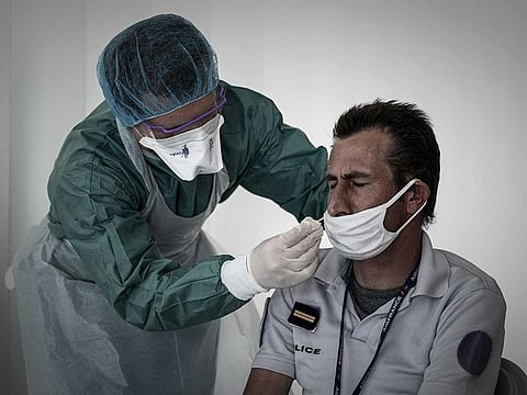 A medical personnel takes a nasal swab from a police officer at a COVID-19 (novel coronavirus) free screening booth set up in the arrival hall of the Bordeaux-Merignac international airport in Merignac, southwestern France, on July 23, 2020. 