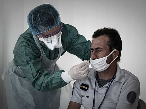 A medical personnel takes a nasal swab from a police officer at a COVID-19 (novel coronavirus) free screening booth set up in the arrival hall of the Bordeaux-Merignac international airport in Merignac, southwestern France, on July 23, 2020. 